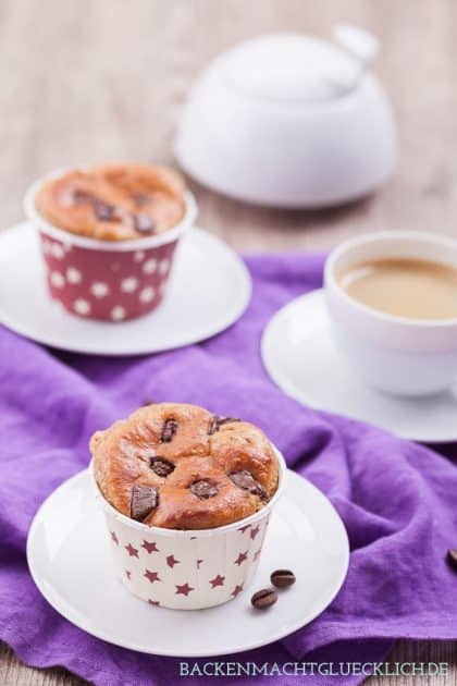 Low-Carb-Proteinmuffins mit Schokostückchen in Papierförmchen neben Kaffeetasse und Kaffeebohnen