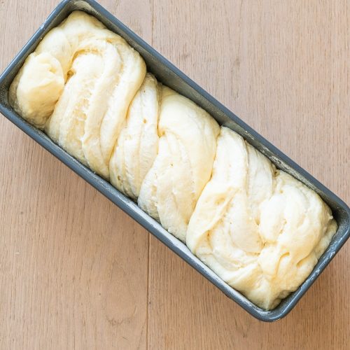 Geflochtener Hefeteig mit Quarkfüllung in Kastenform vor dem Backen
