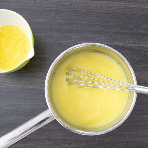 Vanillecreme im Topf mit Schneebesen verrührt neben verquirlter Eiermischung im Messbecher