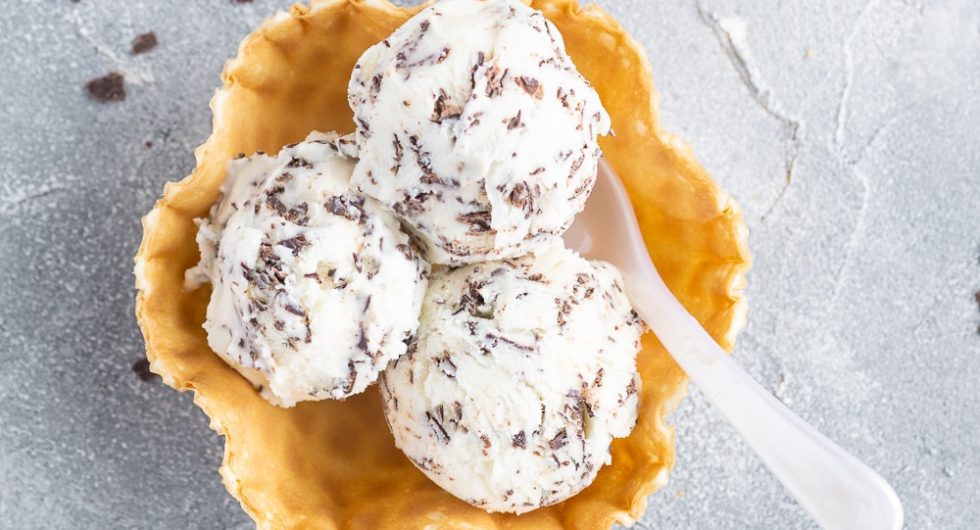 Drei Kugeln Stracciatella-Eis in Waffelschale mit Löffel