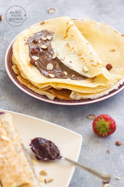 Gefaltete Crêpes mit Nuss-Nougat-Creme und gehackten Haselnüssen, Erdbeere daneben