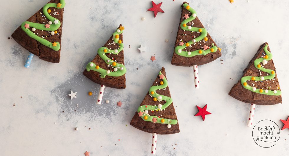 Brownie-Dreiecke als Tannenbäume mit grüner Zuckergussgirlande und Streuseln auf Stäbchen
