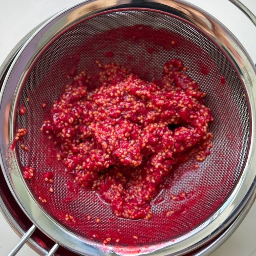 Pürierte Johannisbeeren werden im Metallsieb von den Kernen getrennt