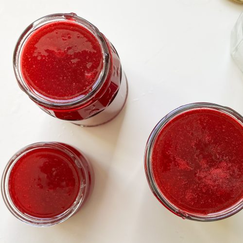 Offene Gläser mit frisch eingefüllter roter Marmelade von oben