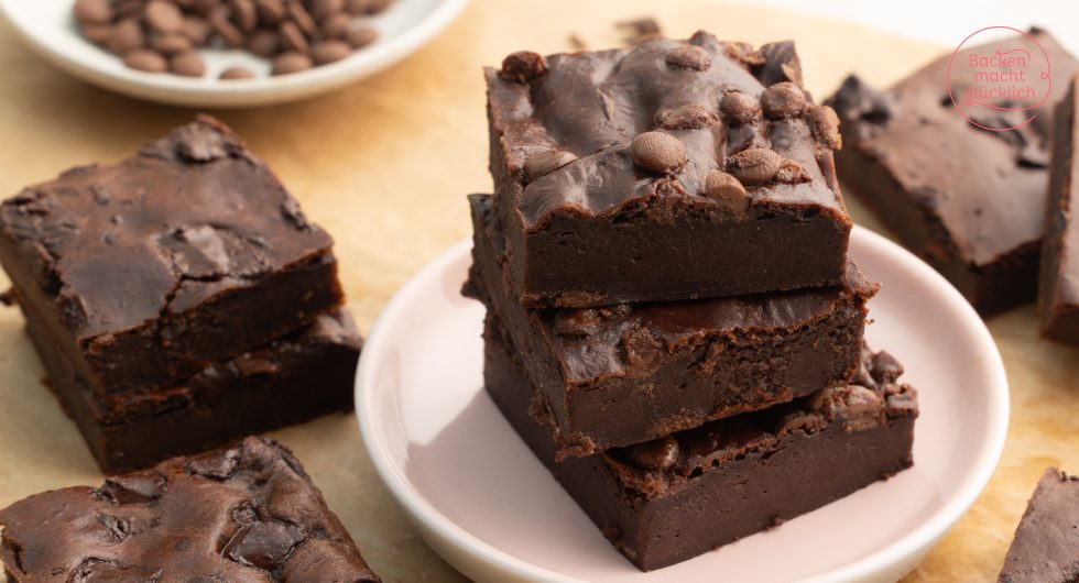 Gestapelte Protein-Brownies mit Schokostückchen auf rosa Teller, Kaffeebohnen im Hintergrund